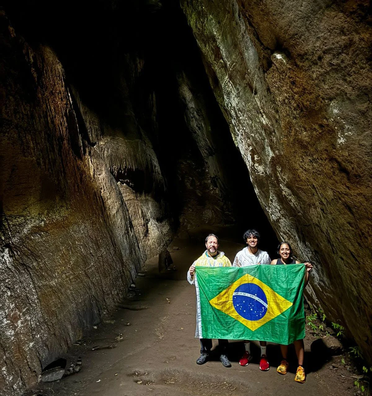 People holding a Brazilian flag in a cave